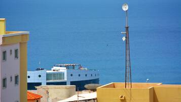 A coastal building with a satellite dish, a ladder, and a view of the sea.
