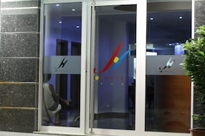 A hotel entrance with a glass door, a logo, and a sign indicating it is a hotel.