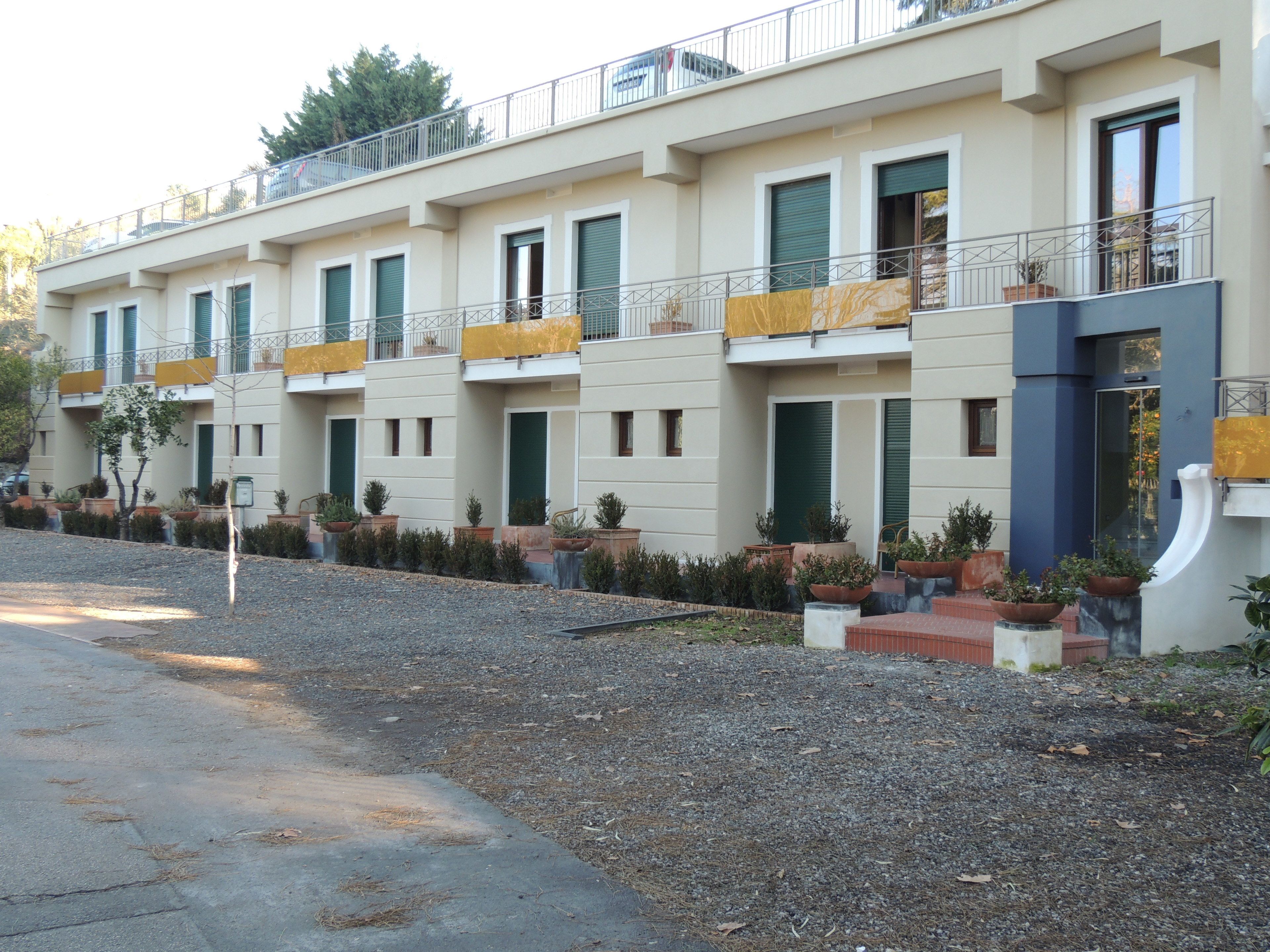 Eine Reihe moderner Apartmentgebäude mit Balkonen, Außenpflanzen und einem Kiesweg.