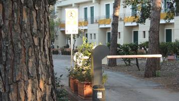 Stroll through the tranquil urban oasis, surrounded by mature trees and lush greenery, to a building with a clean, contemporary design.