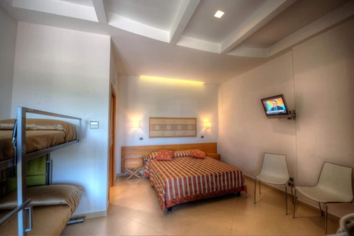 Un dormitorio con literas, una cama individual, un televisor y una silla.