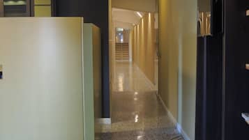 A corridor with a polished floor, leading to a staircase and a door at the end.
