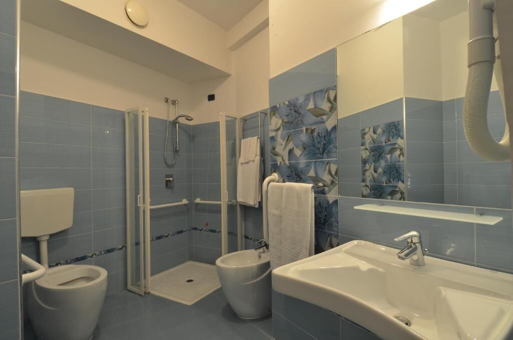 Een badkamer met toilet, bidet en een groot wastafel.