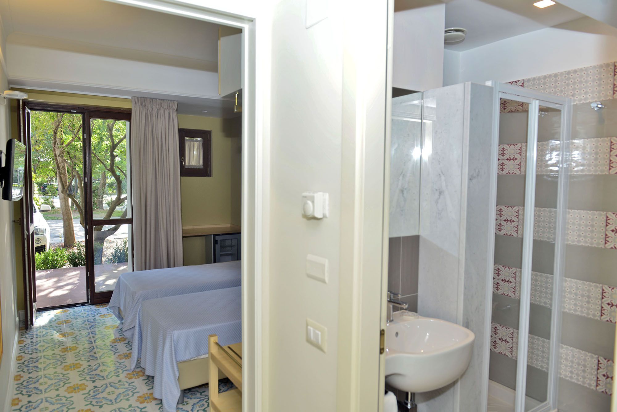 Una habitación de hotel con cama, baño con lavamanos y ducha, y vistas al exterior.
