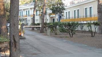 Una calle residencial con árboles y una hilera de edificios blancos con persianas verdes.