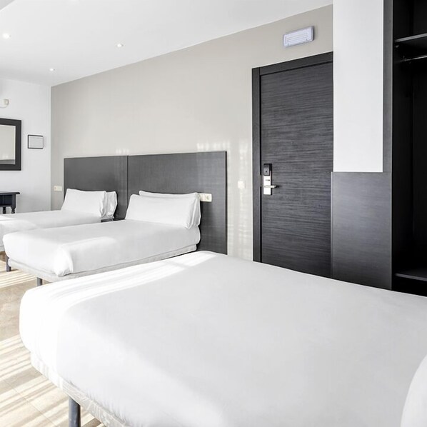 A hotel room with two single beds, a dark wooden door, and a small bedside table. - Hotel Victoria Valdemoro (Valdemoro)