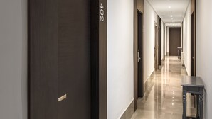 A modern hotel corridor with dark wooden doors, a number '402' on one door, and a small table with a chair on the right. - Hotel Victoria Valdemoro  (Valdemoro)