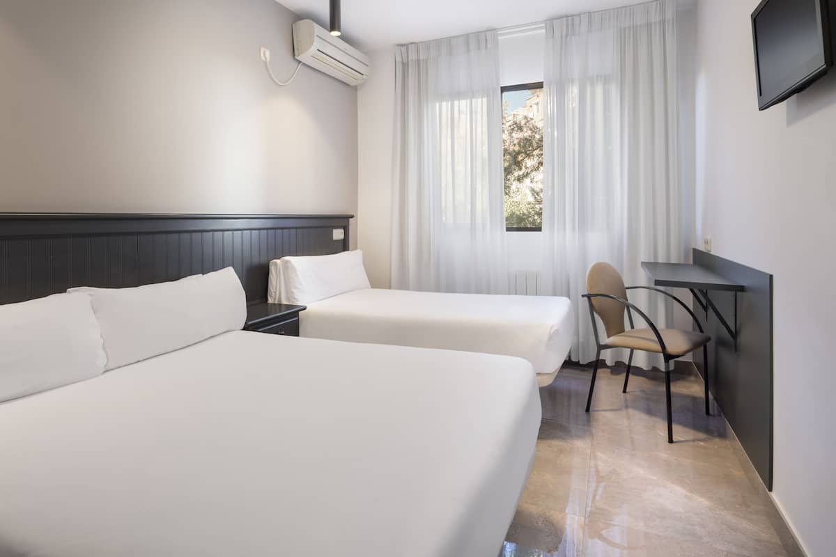 Una habitación de hotel con dos camas, un escritorio, una silla y una televisión.