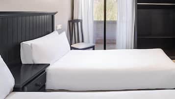 A modern hotel room with a large bed, a nightstand, a chair, and a wardrobe.