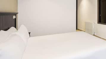 Una cama individual con ropa de cama blanca en una habitación con radiador y ventana.