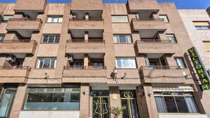 A multi-story building with a brick facade, balconies, and a storefront with a sign that reads "VICTORIA". - Hotel Victoria Valdemoro  (Valdemoro)