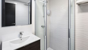 A modern bathroom with a glass-enclosed shower, a white sink, and a large mirror. - Hotel Victoria Valdemoro  (Valdemoro)