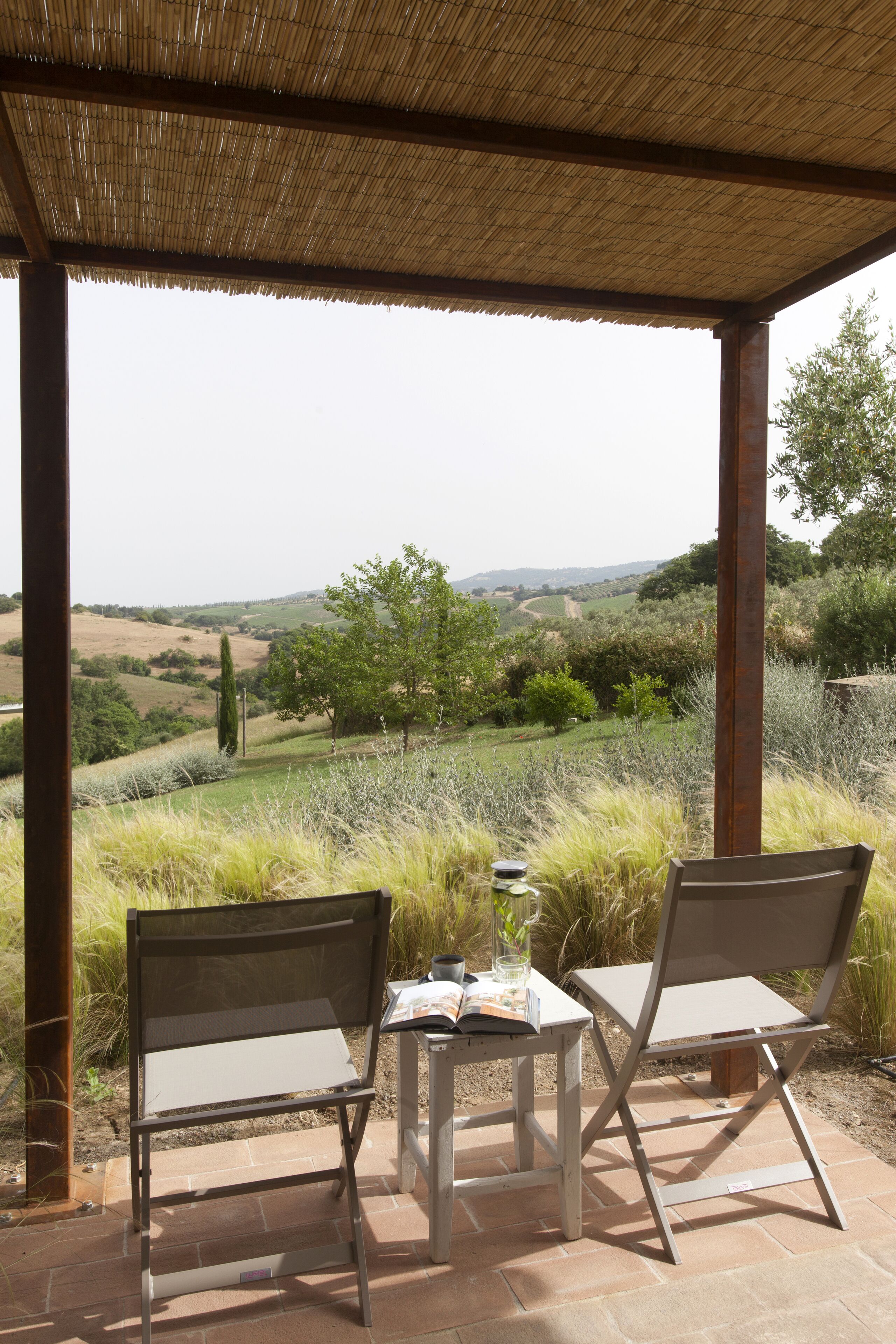 Un espacio al aire libre con dos sillas y una mesa, con vistas a un paisaje pintoresco.