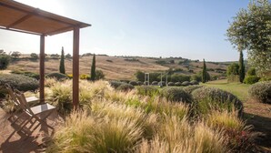 A covered outdoor seating area with a view of rolling hills and distant trees. - Casale Sterpeti (Magliano in Toscana)