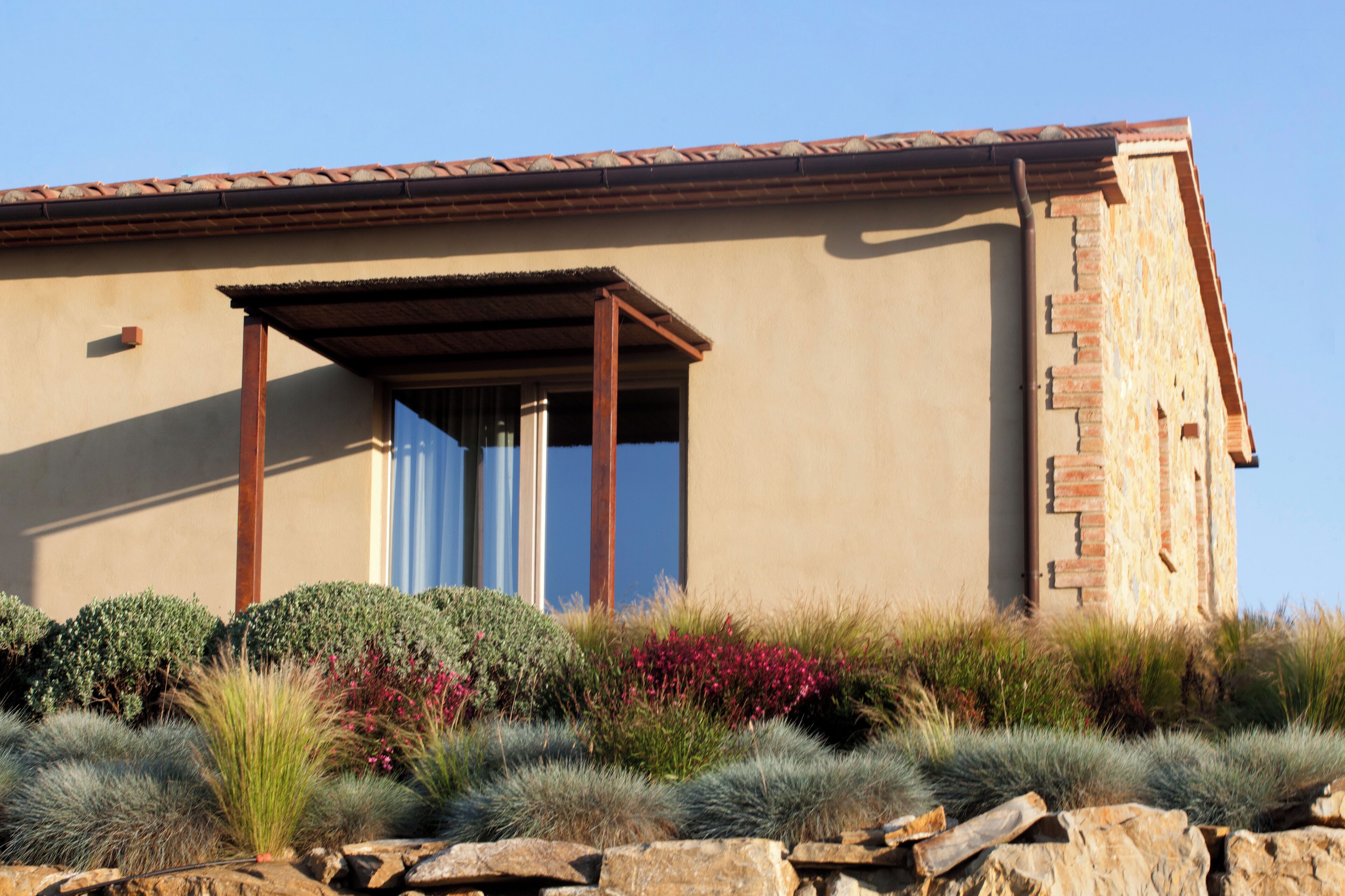 A modern building with a flat roof, a covered patio area, and a stone facade.