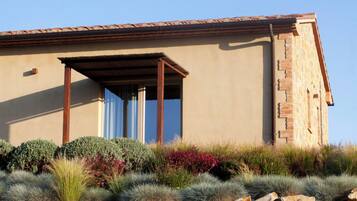 A modern building with a flat roof, a covered patio area, and a stone facade.