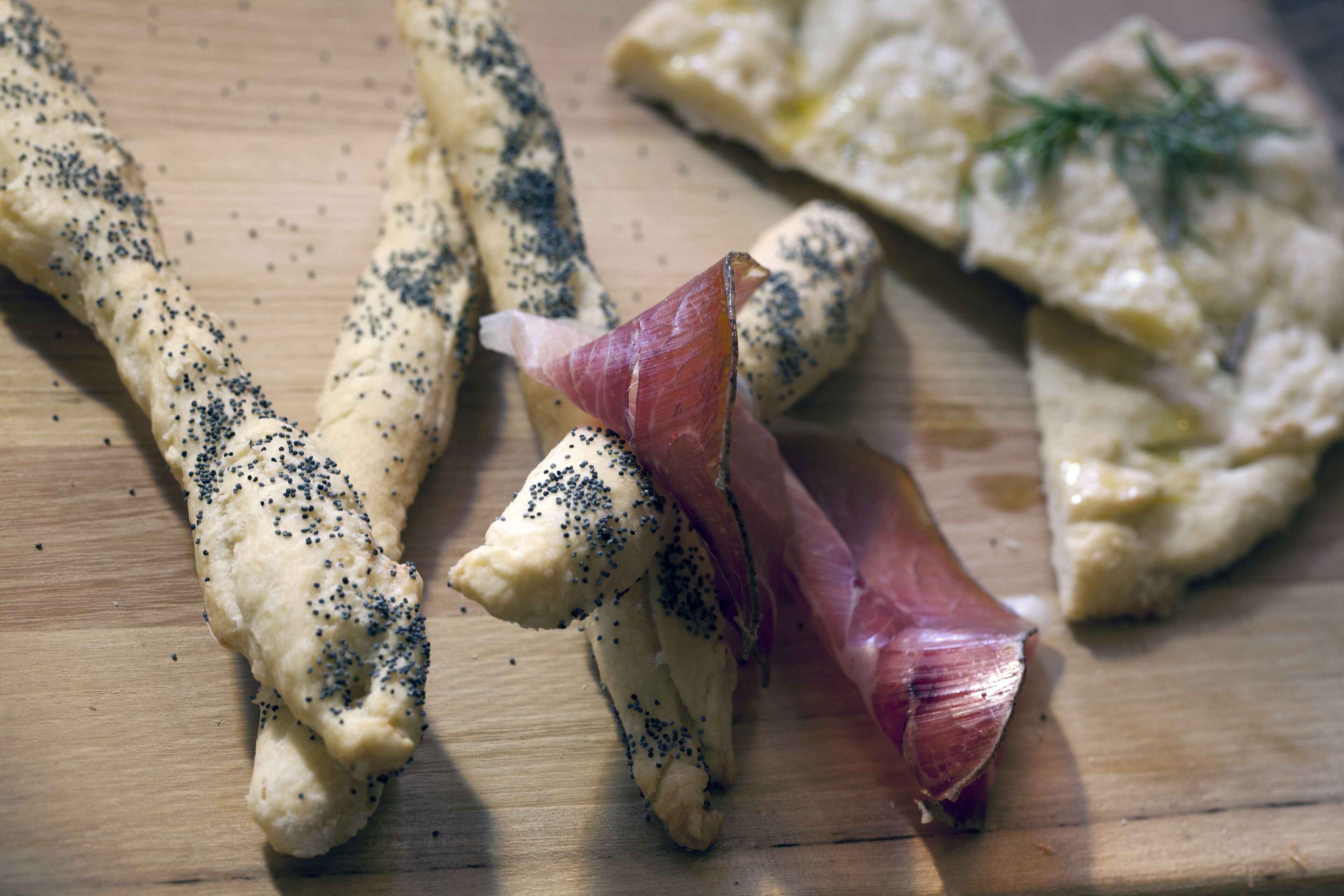 Ein Holzschnittbrett mit verschiedenen Lebensmitteln, darunter Brot und eine Scheibe Wurst.