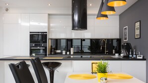 Una cocina moderna con armarios blancos, encimera negra y manteles individuales amarillos en la mesa de comedor.