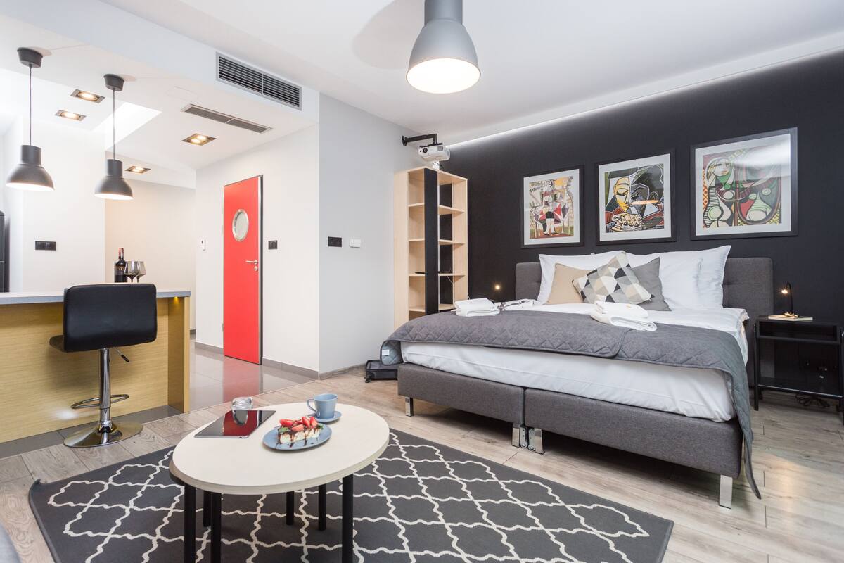 A modern hotel room with a bed, bedside table, and a desk area.