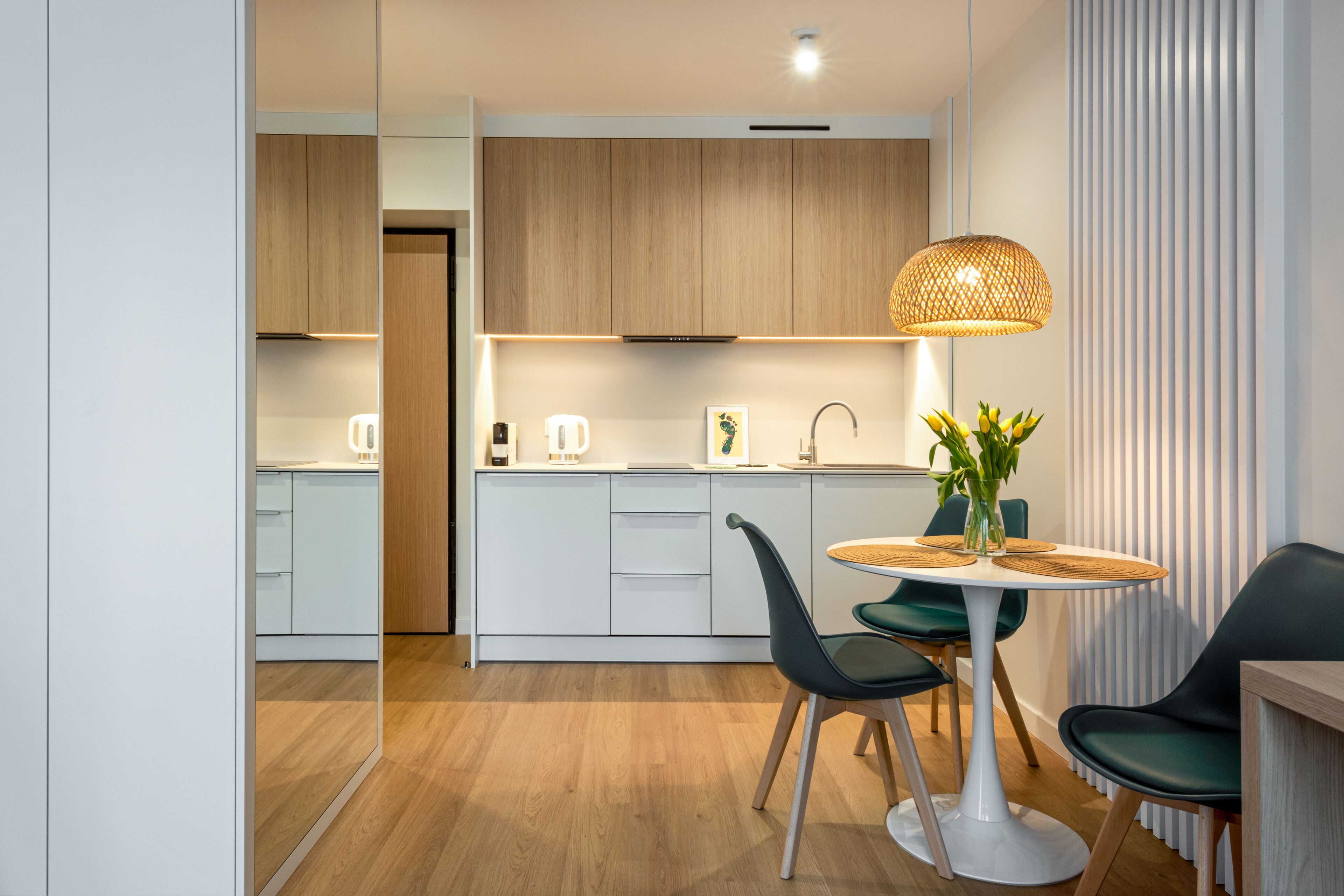 Una cocina moderna con armarios blancos, encimera de madera y comedor con una mesa redonda y sillas.