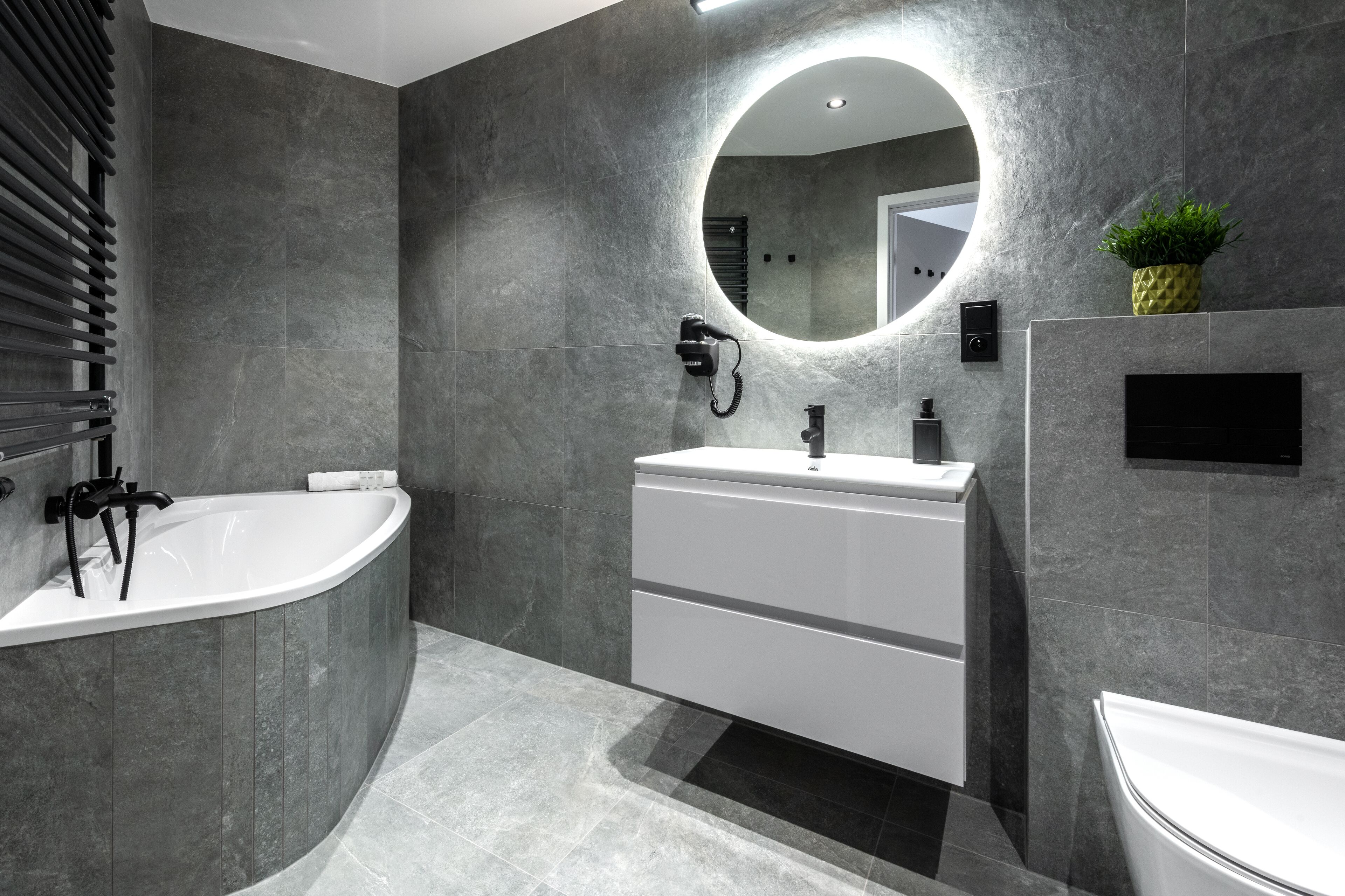 A modern bathroom with a freestanding bathtub, a vanity with a mirror, and a toilet.