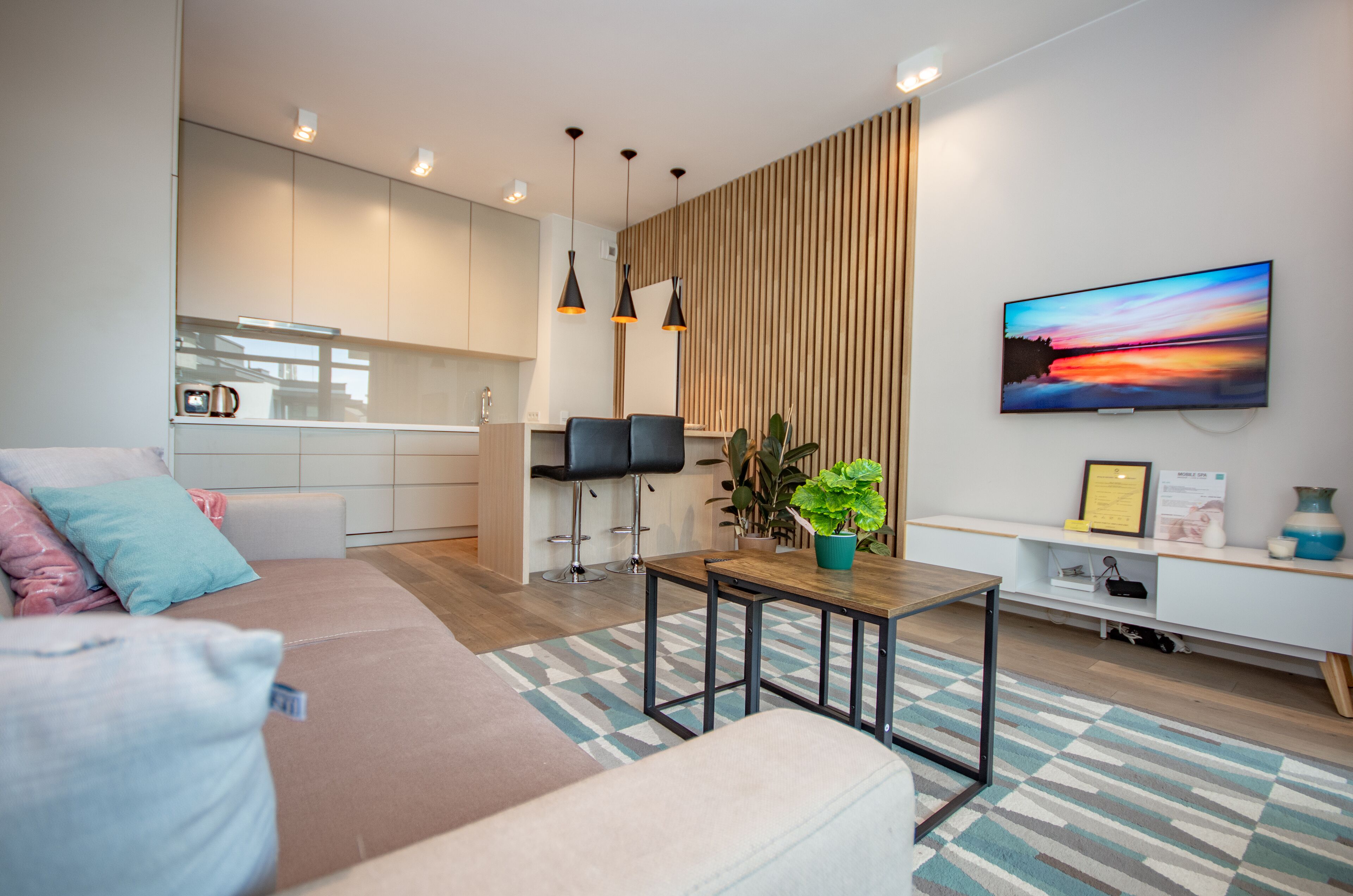 A modern living room with a sofa, a coffee table, and a TV mounted on the wall.