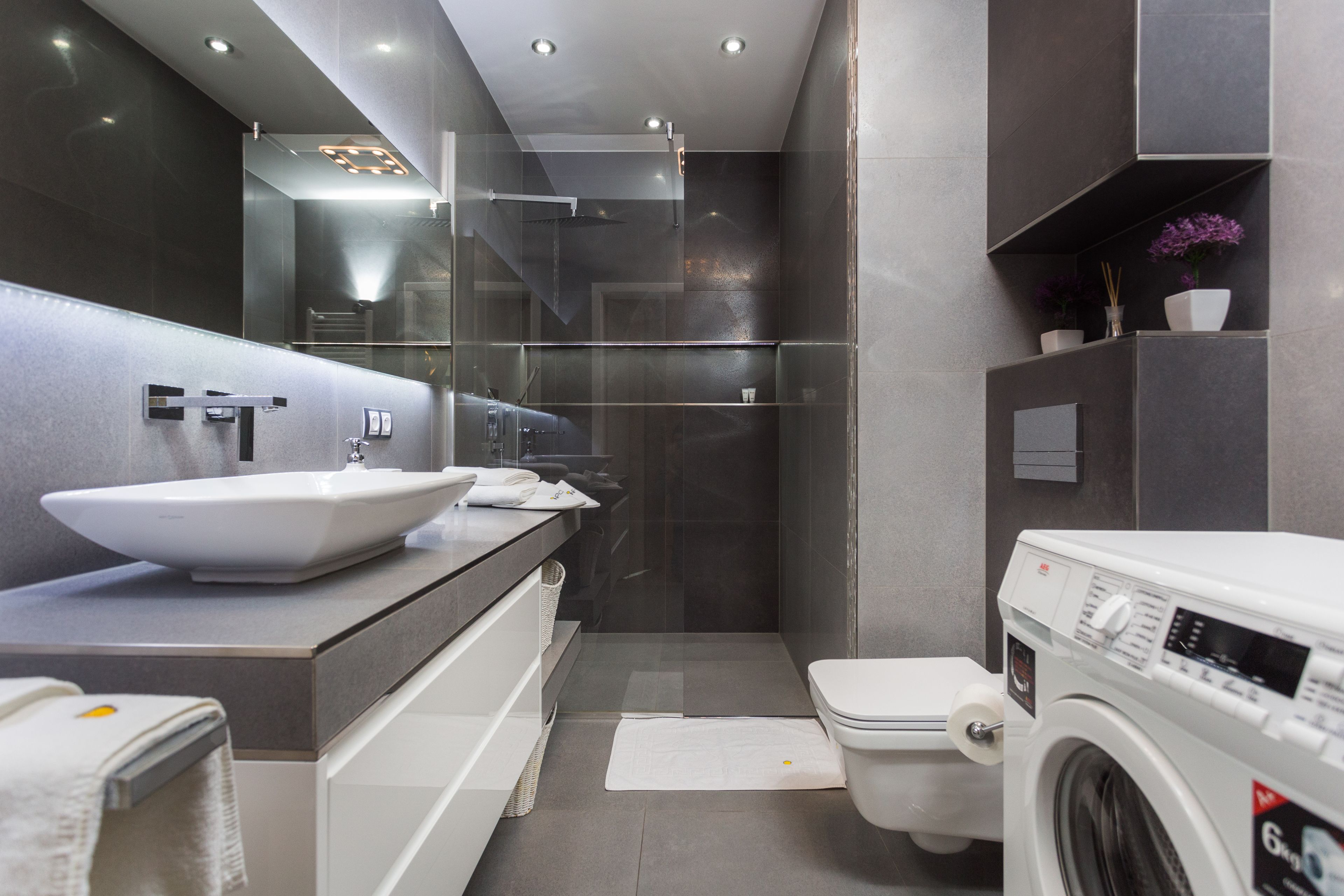 Une salle de bain moderne avec un grand lavabo, des toilettes et un lave-linge.