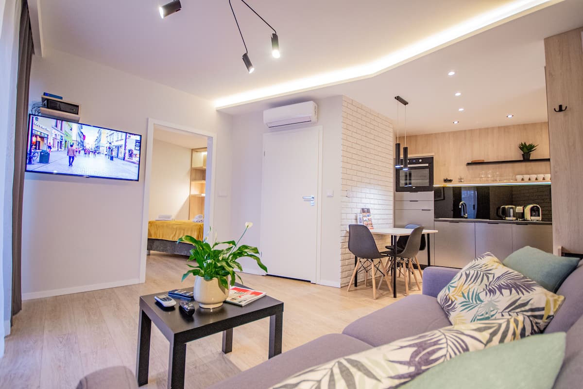 A modern living room with a sofa, a coffee table with a plant, and a TV displaying a street scene.