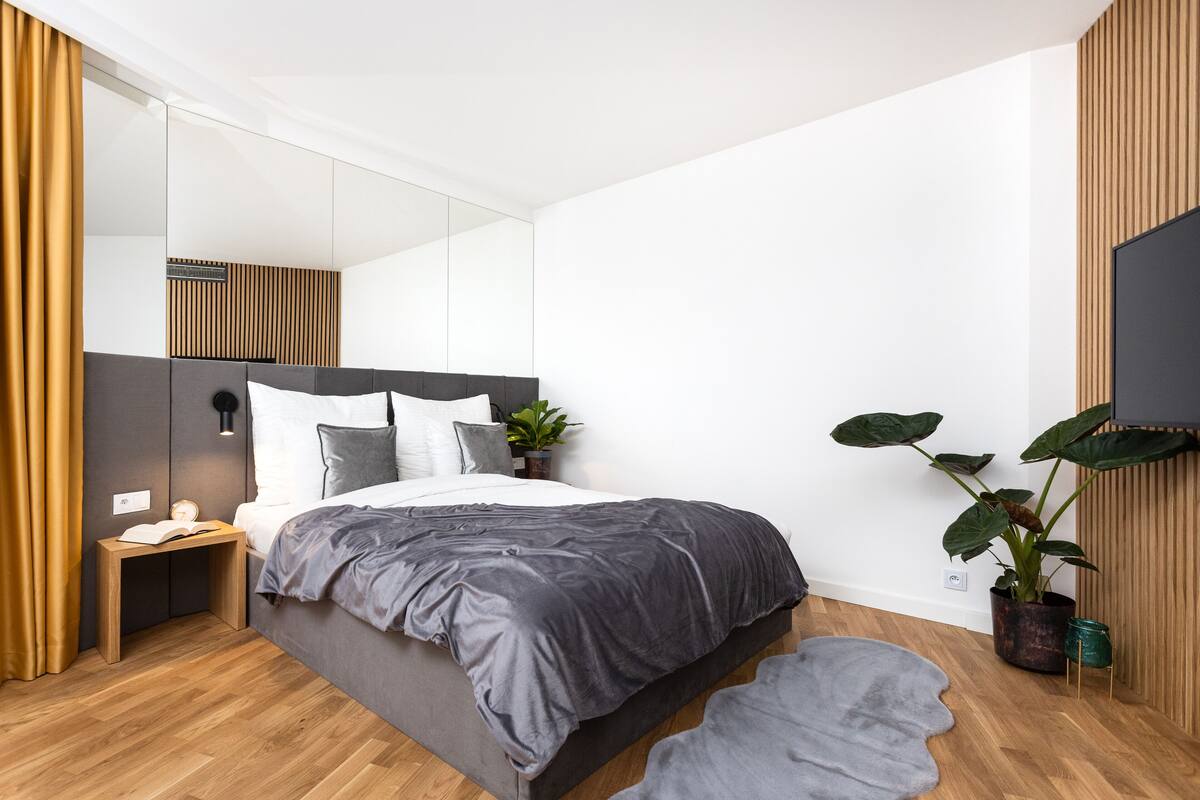 A modern bedroom with a bed, bedside table, and a potted plant.