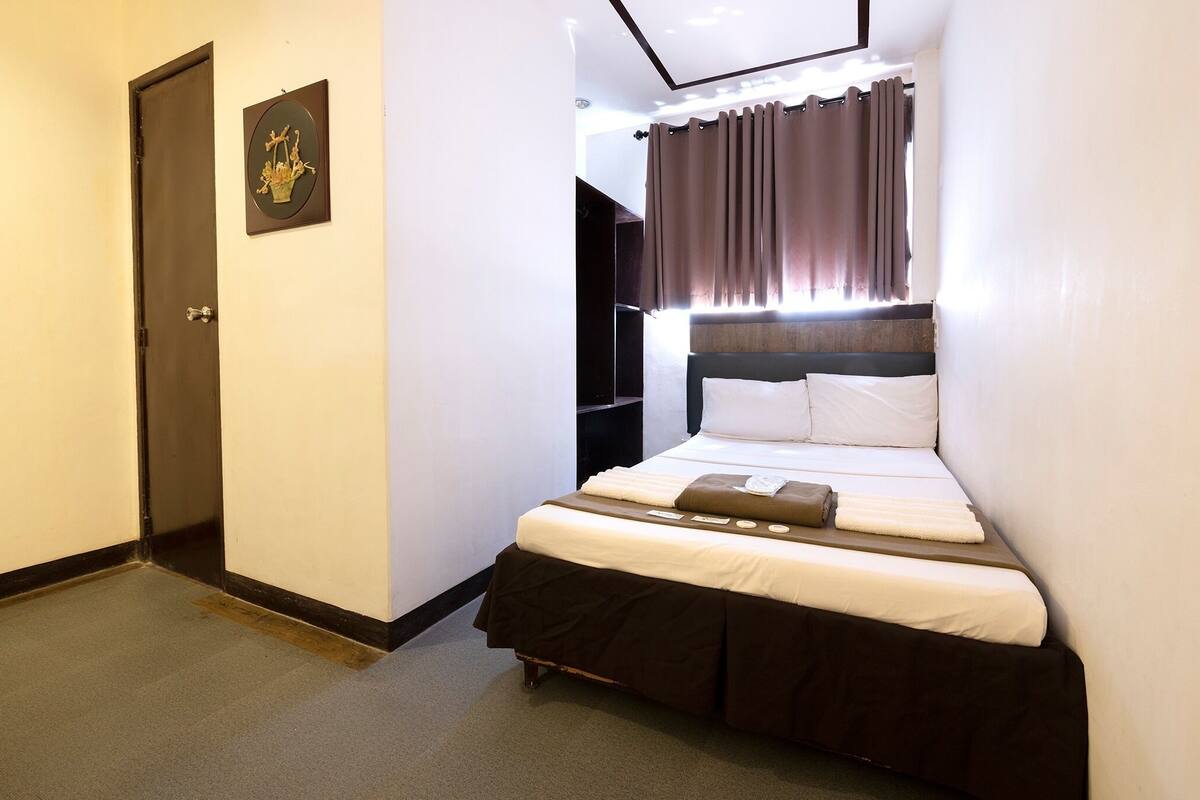 Una habitación de hotel con una cama, una puerta y un cuadro colgado en la pared.