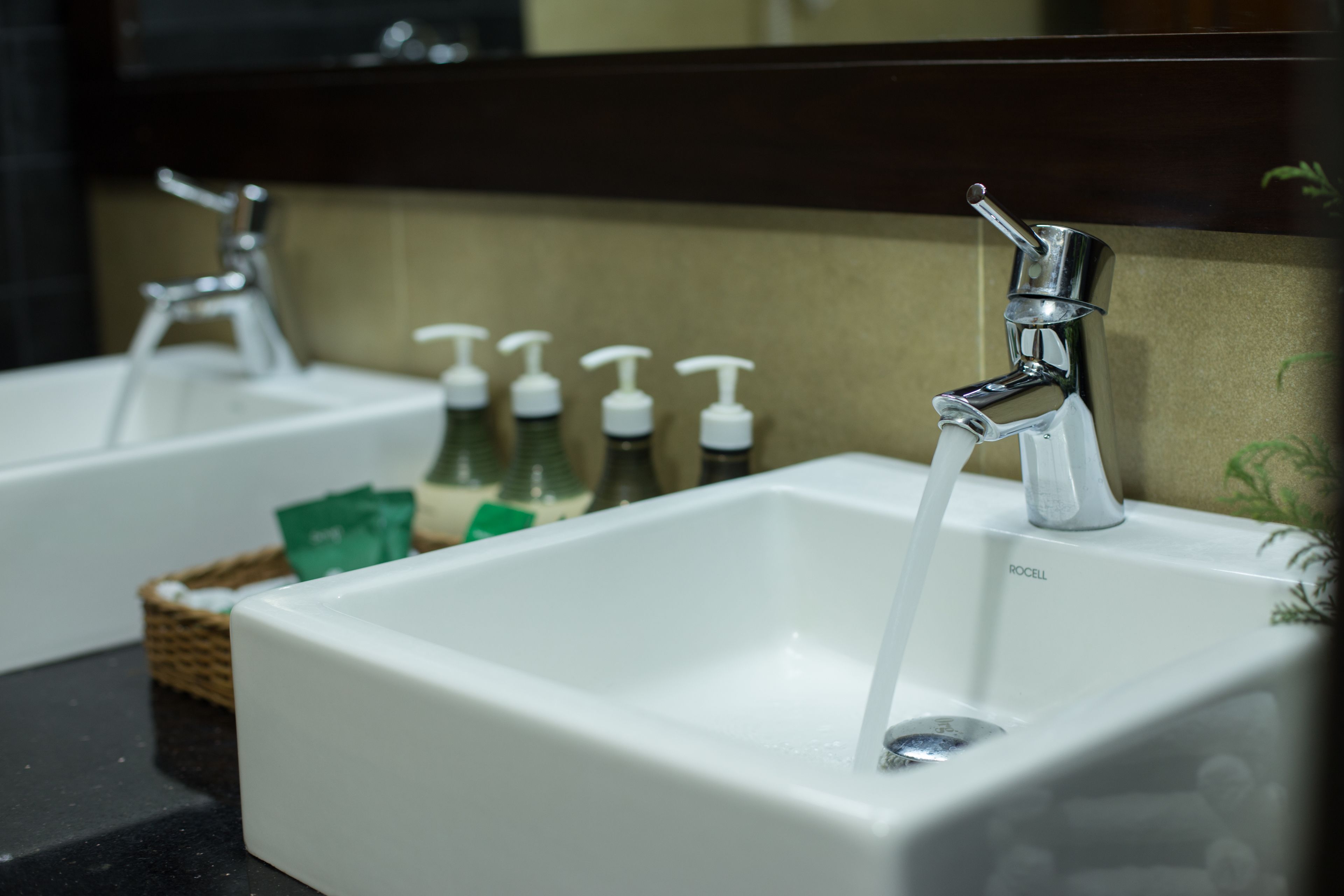 Un baño con dos lavamanos, cada uno con un grifo y dispensadores de jabón.