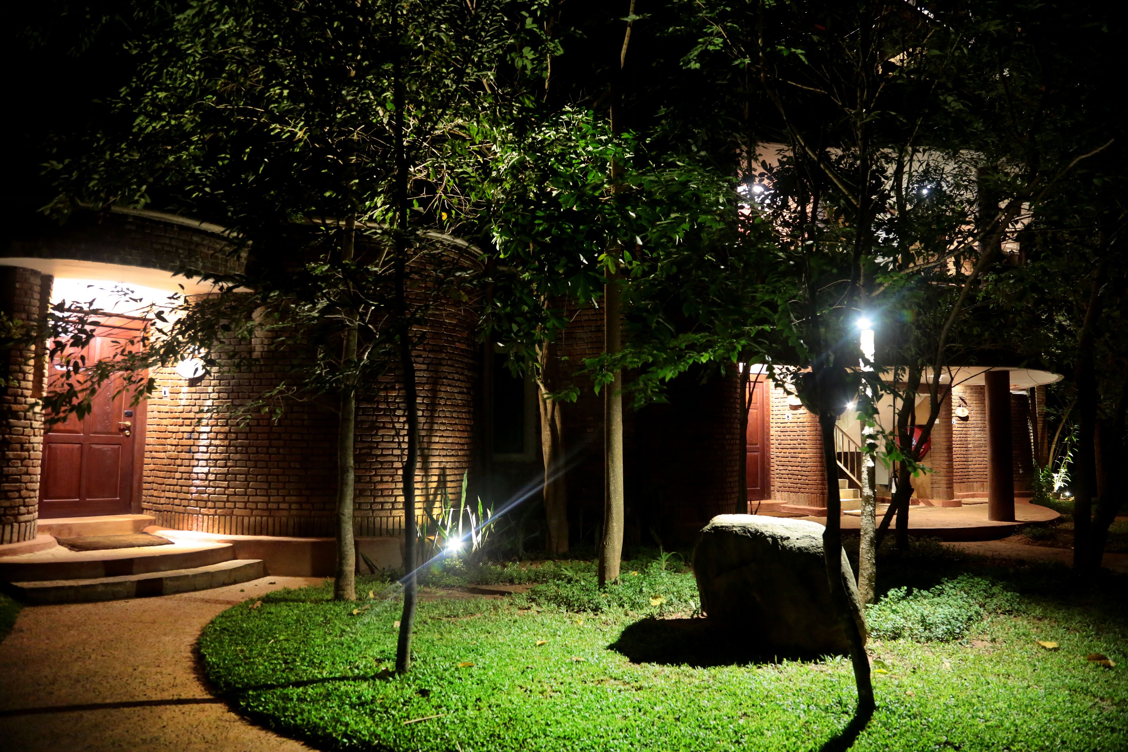 A well-lit brick building with a red door and steps leading to the entrance.