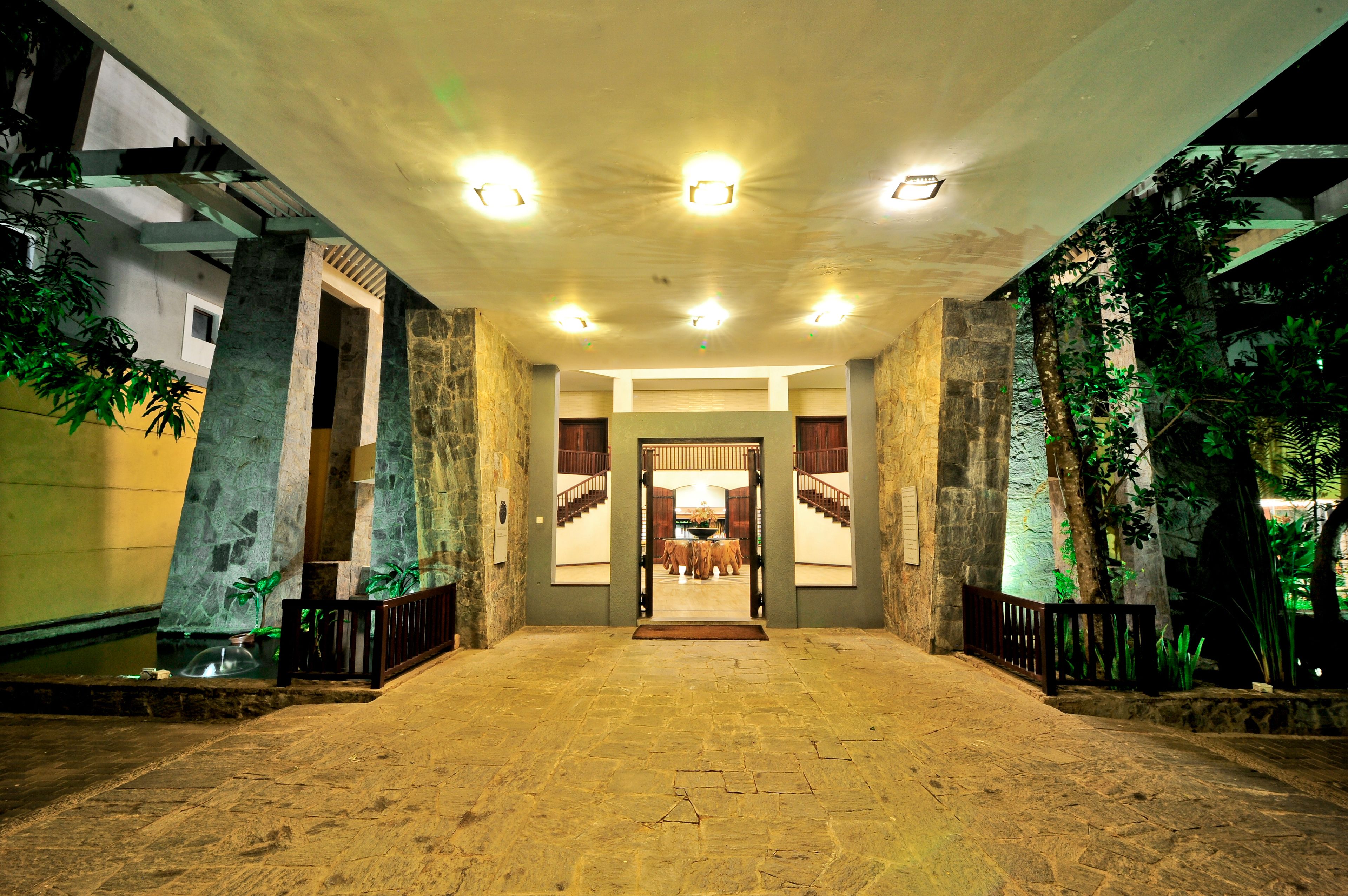 A spacious lobby with a stone floor, a central staircase, and a view into a dining area.