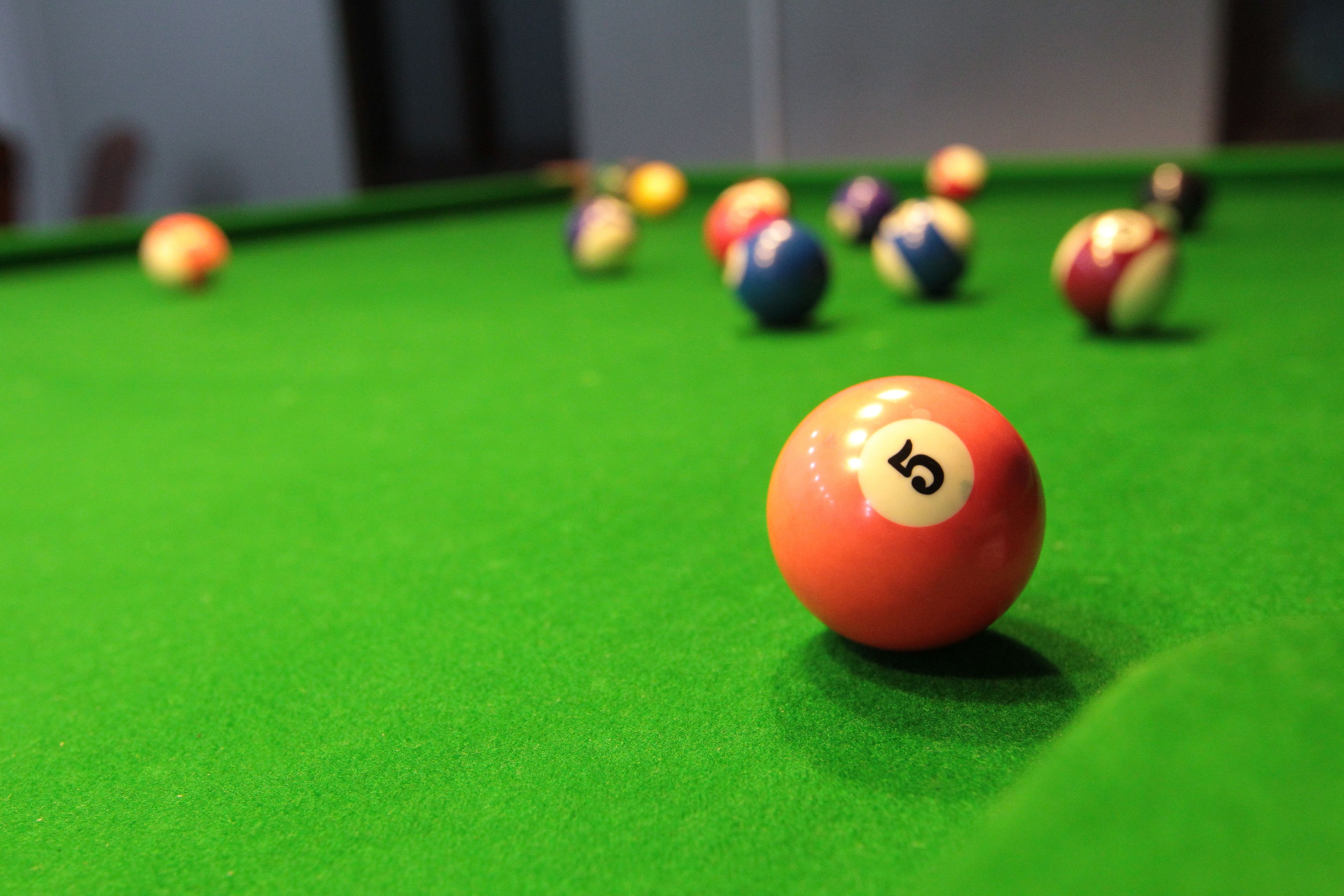 A close-up of a pool table with a red ball marked with a number.