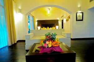 A hotel lobby with a sofa, a coffee table with fruit, and a fireplace.