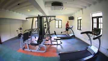 Un gimnasio con cintas de correr, máquinas de pesas y un amplio ventanal que proporciona luz natural.