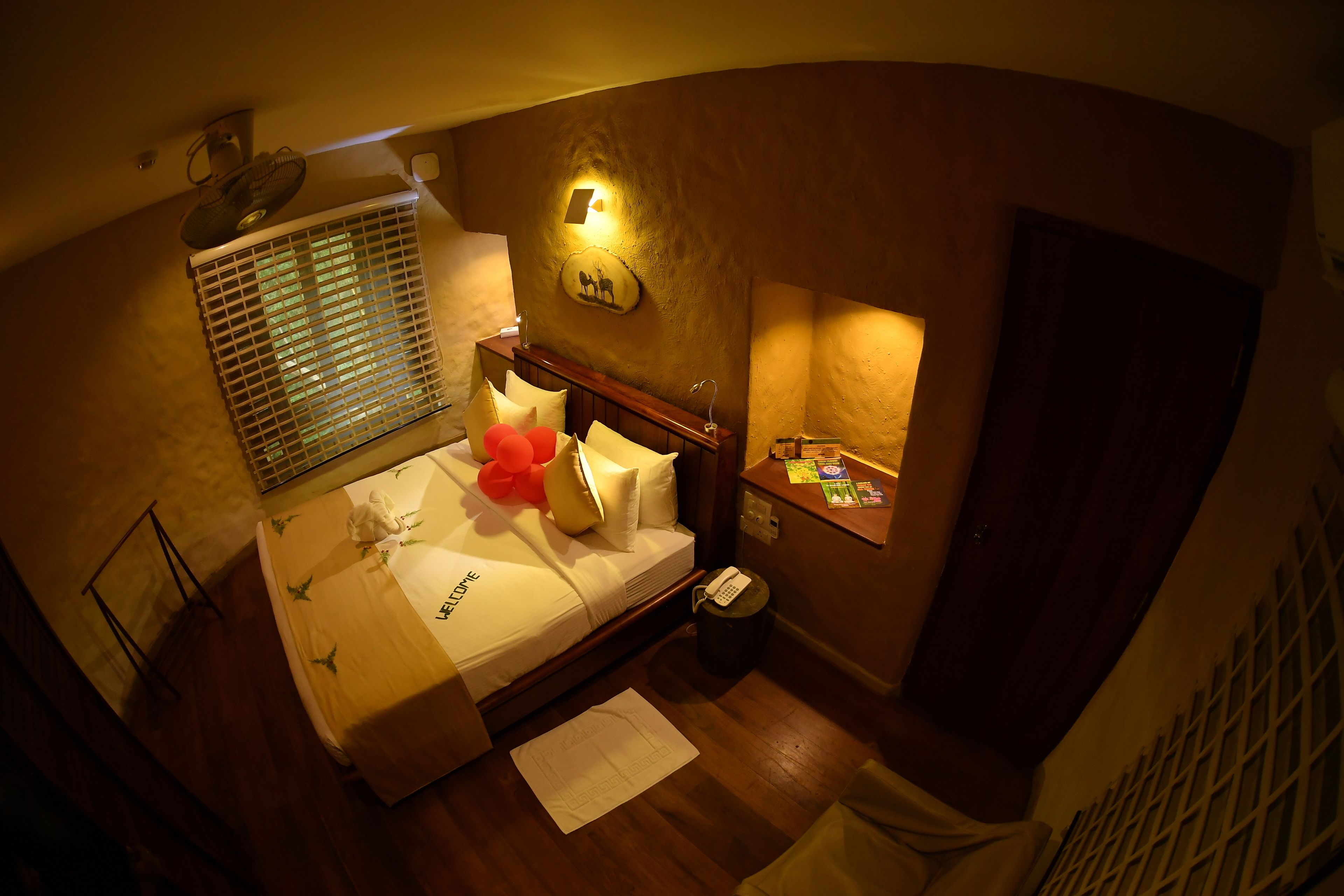 A hotel room with a bed, bedside table, and a small desk with a telephone.