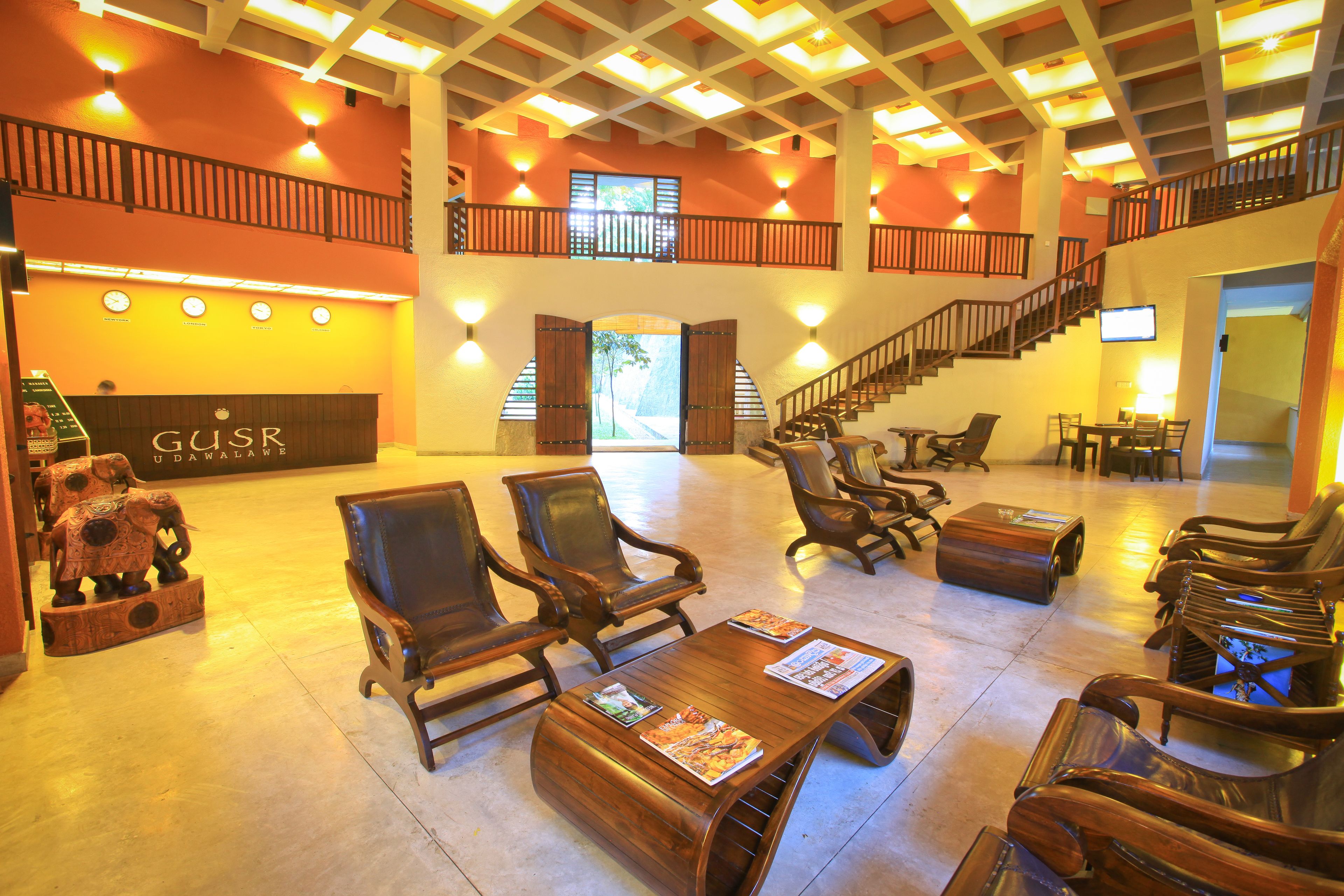A lobby with wooden furniture, a reception desk, and a staircase.