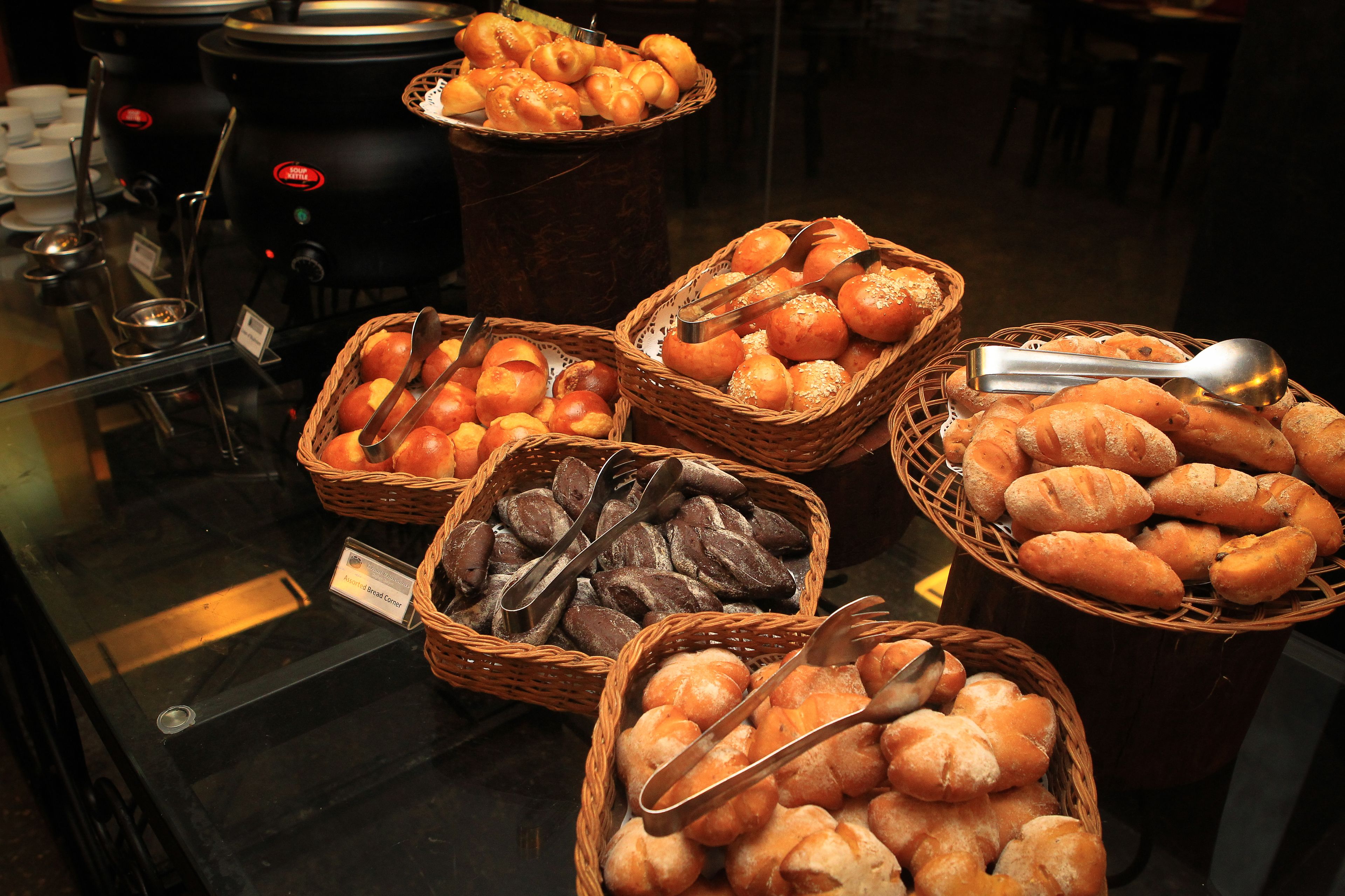 A buffet with various breads and pastries displayed in baskets.