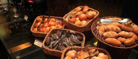 Un buffet proposant une variété de pains et de viennoiseries présentés dans des paniers.