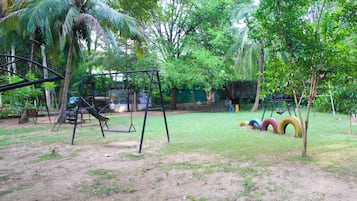 A playground with swings and tire swings in a grassy area with trees.