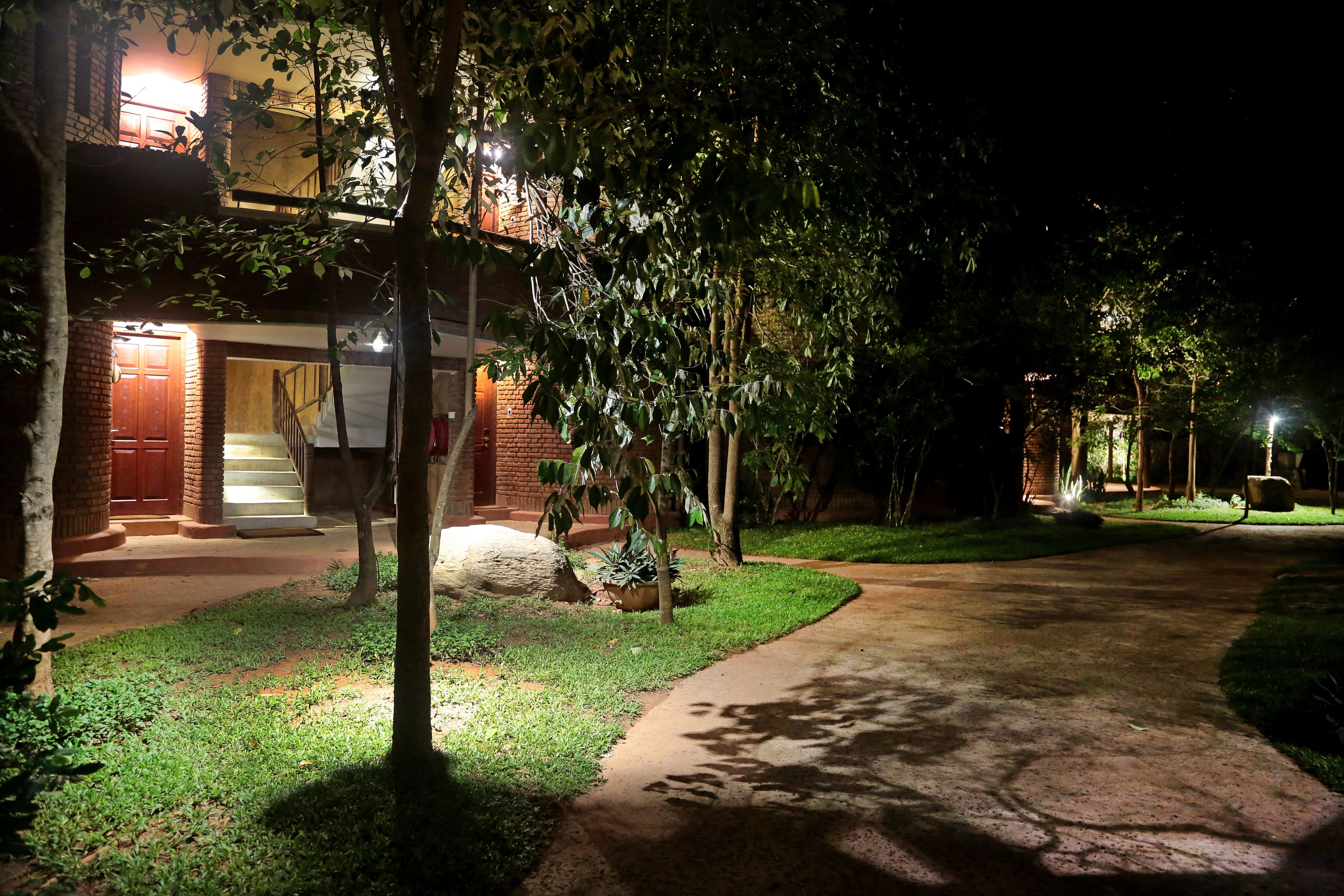 Un sendero bien iluminado que conduce a un edificio con fachada de ladrillo y una escalera visible.