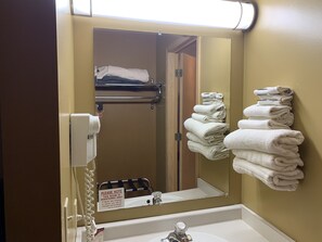 A hotel bathroom with a sink, mirror, towel rack, and a sign indicating daily inventory.