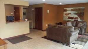 A living room with a brown sofa, a coffee table, and a painting on the wall. - Lakeside Motor Inn (Gladstone)