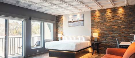 Une chambre d’hôtel moderne dotée d’un grand lit, d’un mur décoratif en pierre et d’un balcon avec vue.