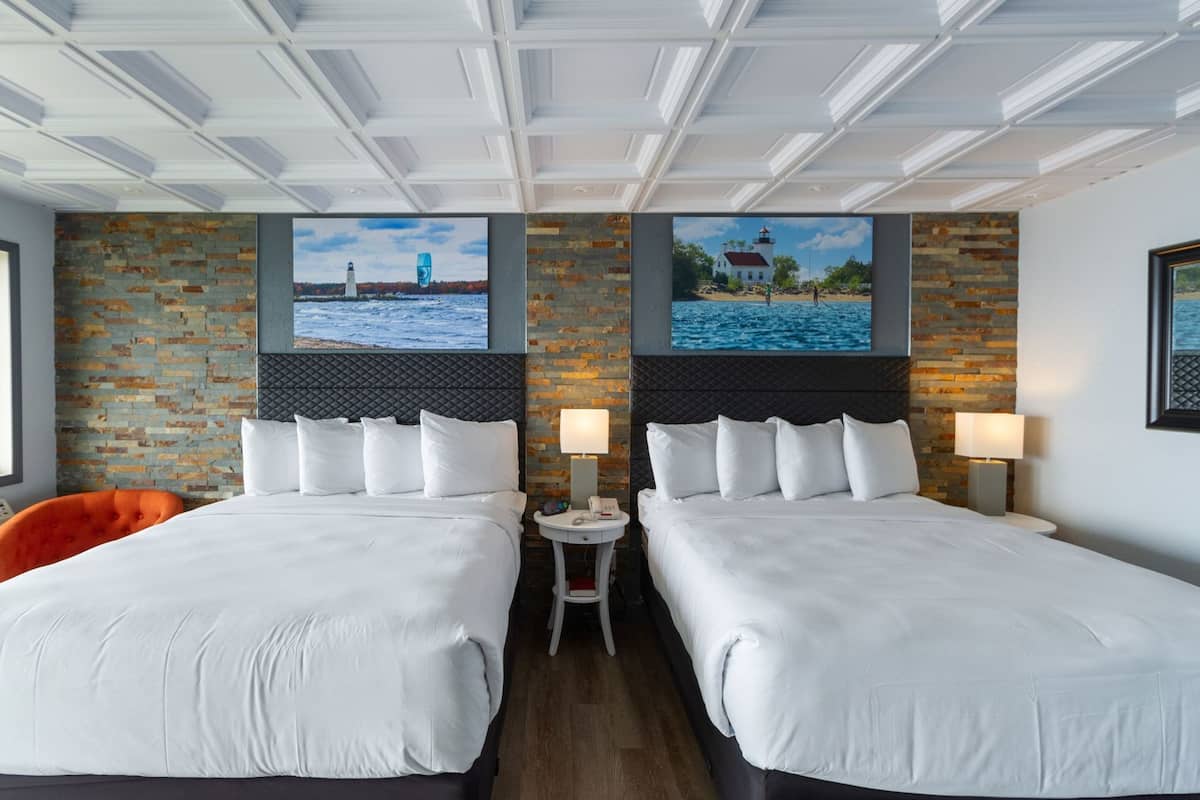 A hotel room with two beds, a brick wall, and a view of a lighthouse.
