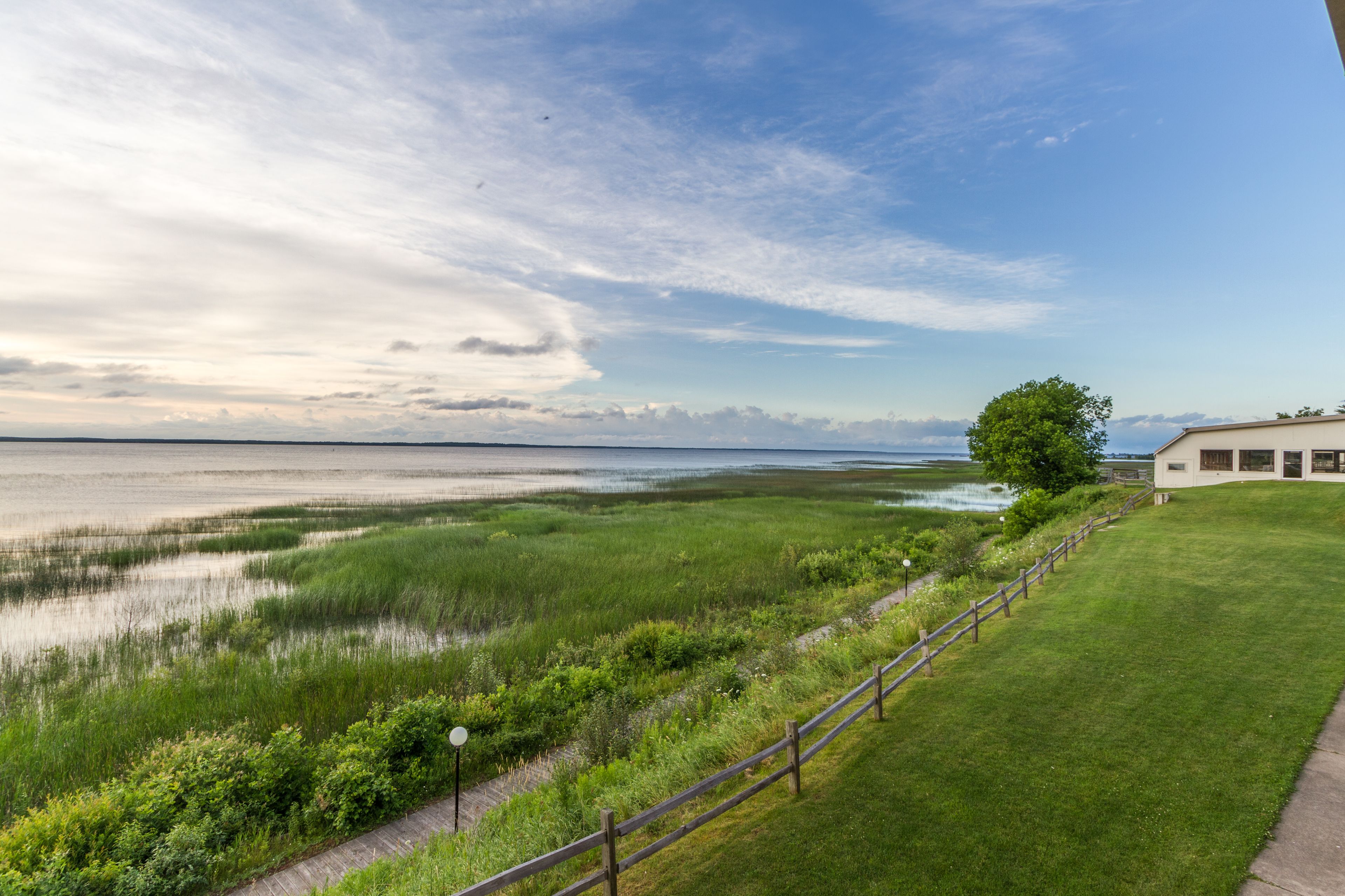 Een kustlandschap met een grasveld, een houten hek en een gebouw met een witte gevel.