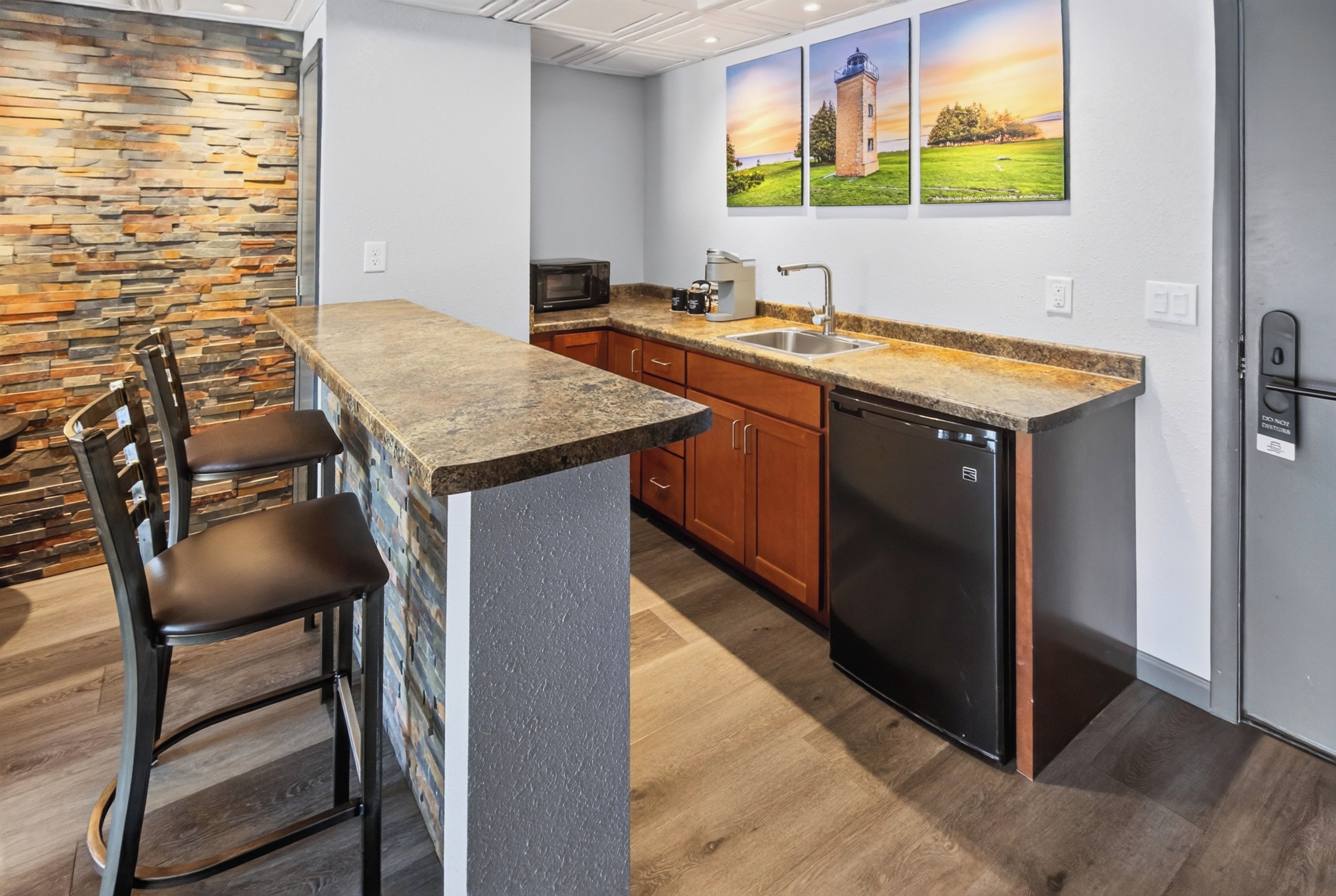 A compact kitchen with a granite countertop, wooden cabinets, a built-in dishwasher, and a stone wall backsplash.