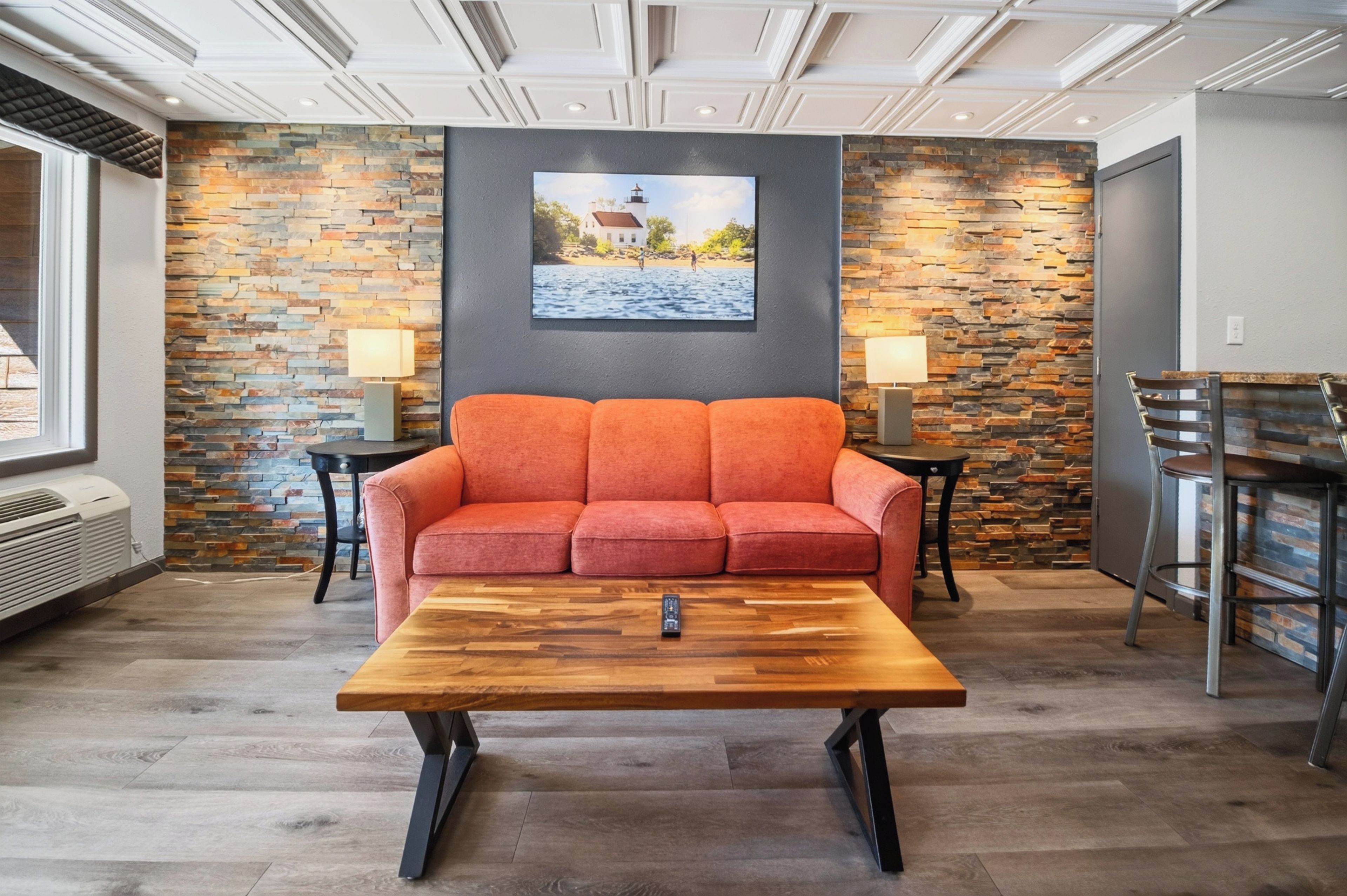 A room with a sofa, a coffee table, a painting on the wall, and a stone wall.