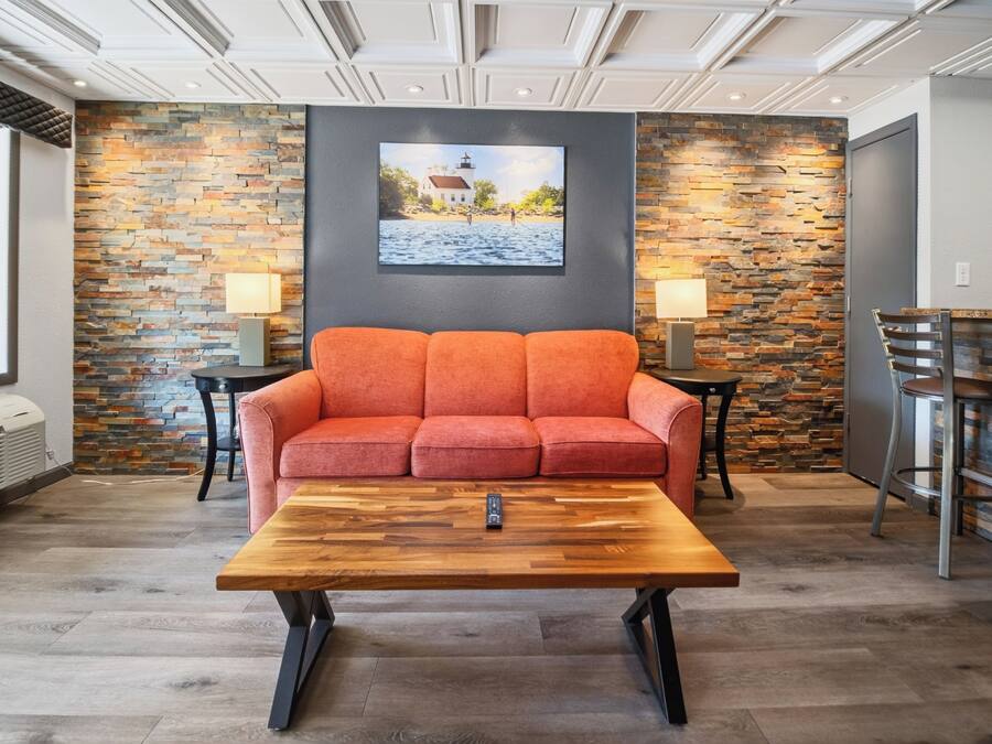 A room with a sofa, a coffee table, a painting on the wall, and a stone wall.